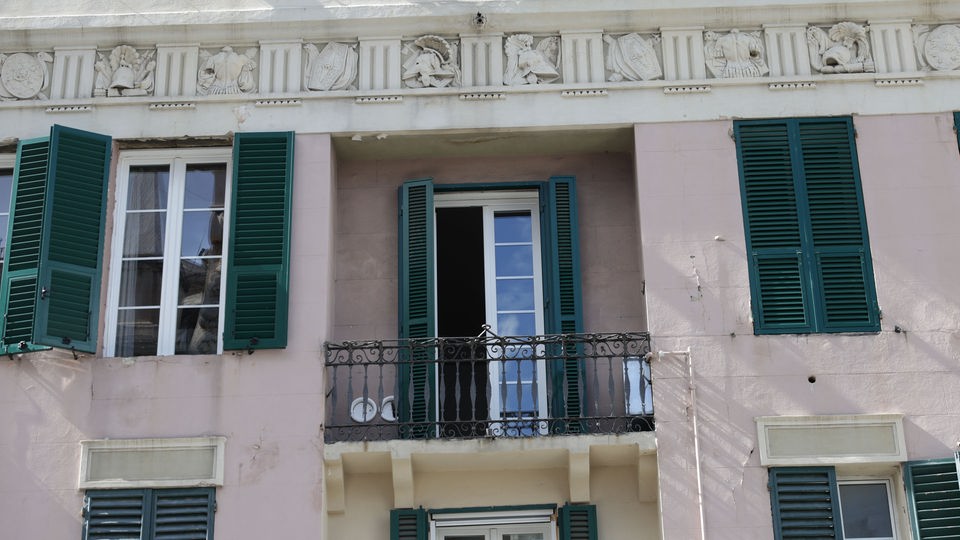 Ausschnitt Hausfassade mit Fensterläden und kleinem Balkon.