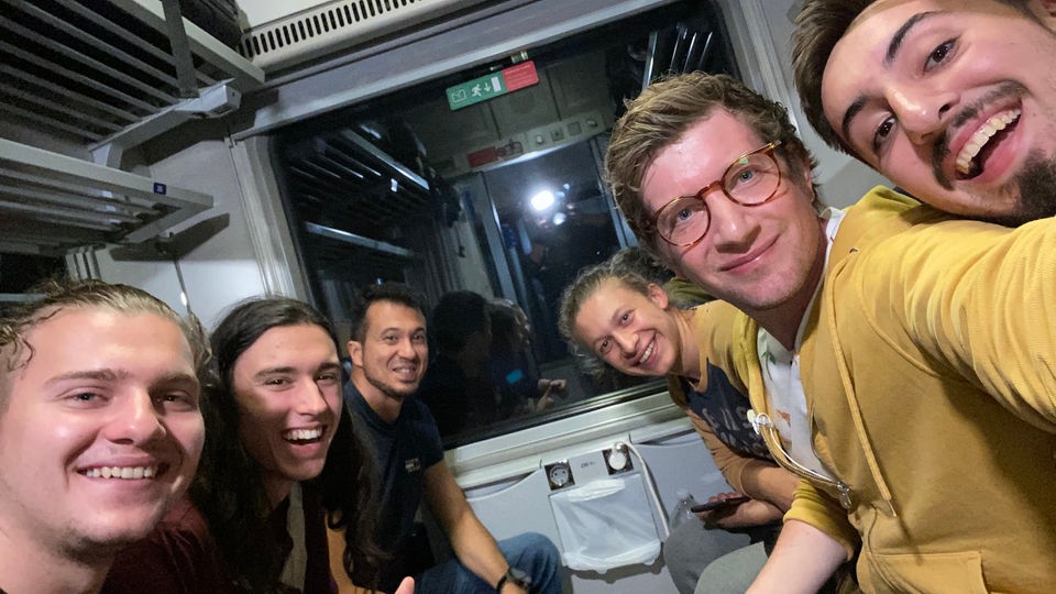 Selfie von Robert und einer Gruppe Mitreisender in Zugabteil.