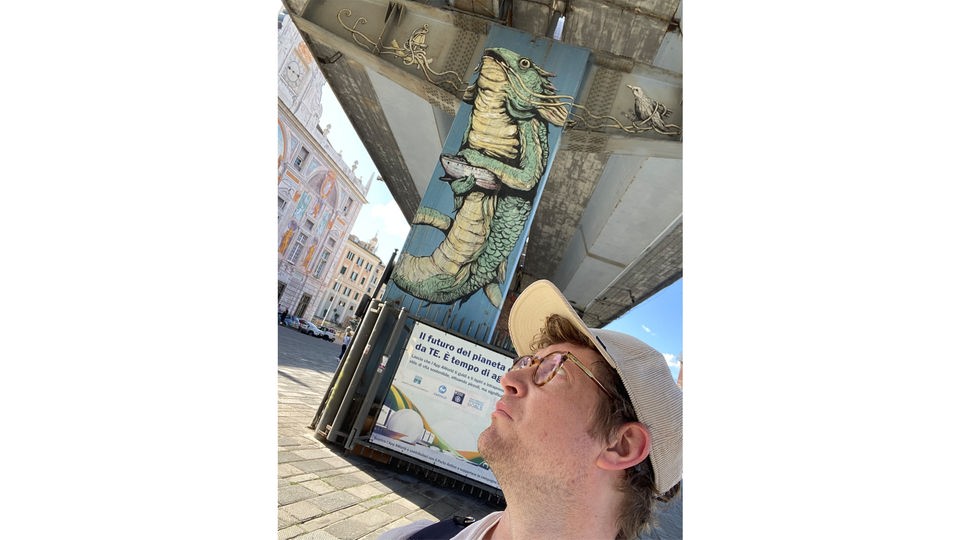 Selfie von Robert vor einem Brückenpfeiler auf den ein Reptil gemalt ist.
