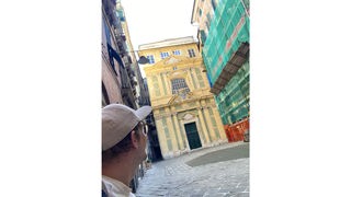 Robert (angeschnitten) steht vor einem gelben Gebäude in Genua.