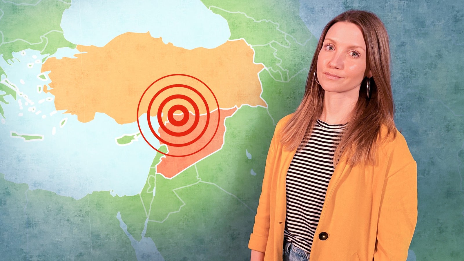 Jana steht vor einer Wand, auf der eine Karte von der Türkei und Syrien eingeblendet ist. Auf der Karte ist eingezeichnet, wo sich das Erdbeben am 06.02.2023 ereignet hat.