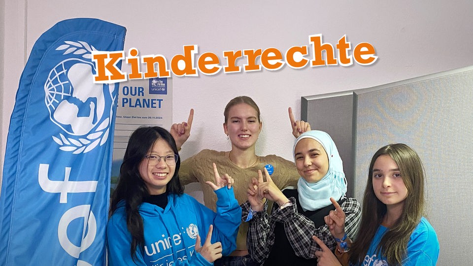 Vier Jugendliche zeigen mit den Fingern nach oben, wo das Wort "Kinderrechte" steht.