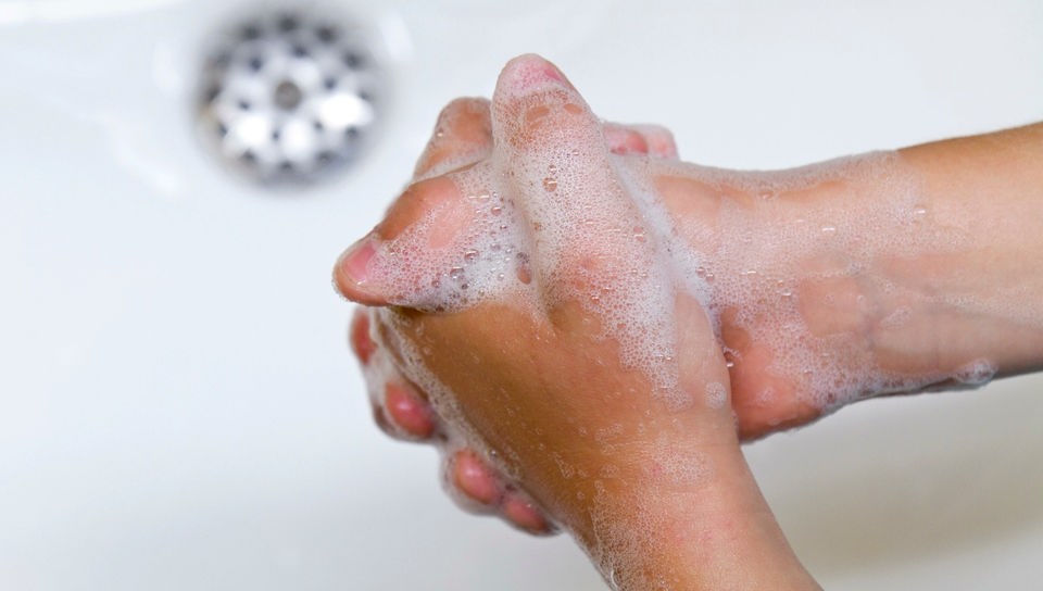 Hände beim Einseifen über einem Waschbecken.