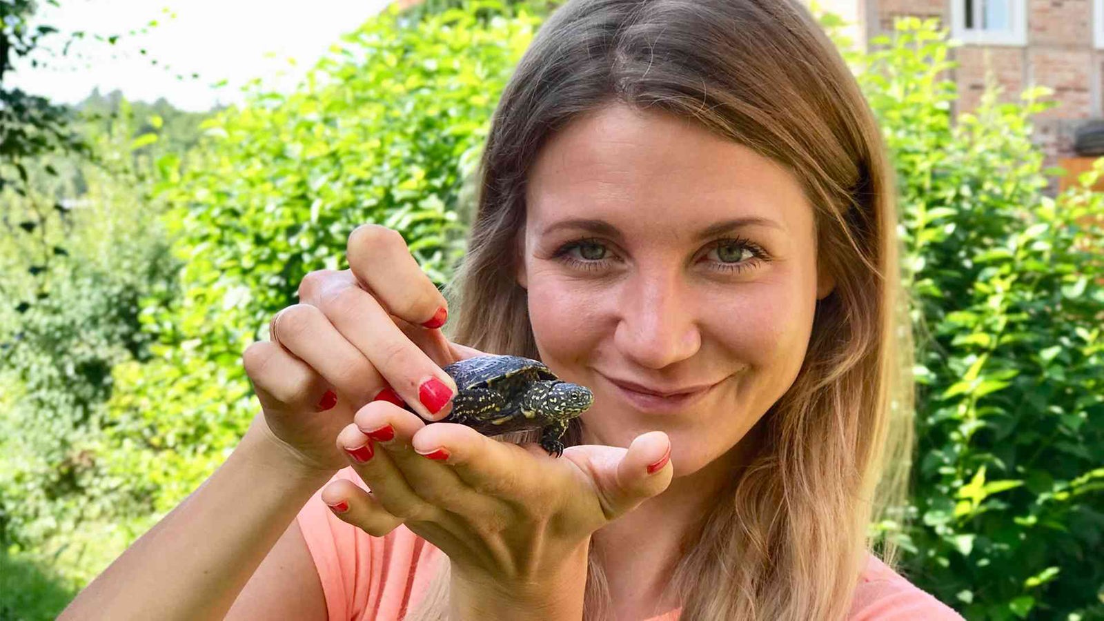 Jana hält eine zwei Jahre alte Europäische Sumpfschildkröte auf der Hand / Jana hält eine junge Europäische Sumpfschildkröte auf der Hand in die Kamera.