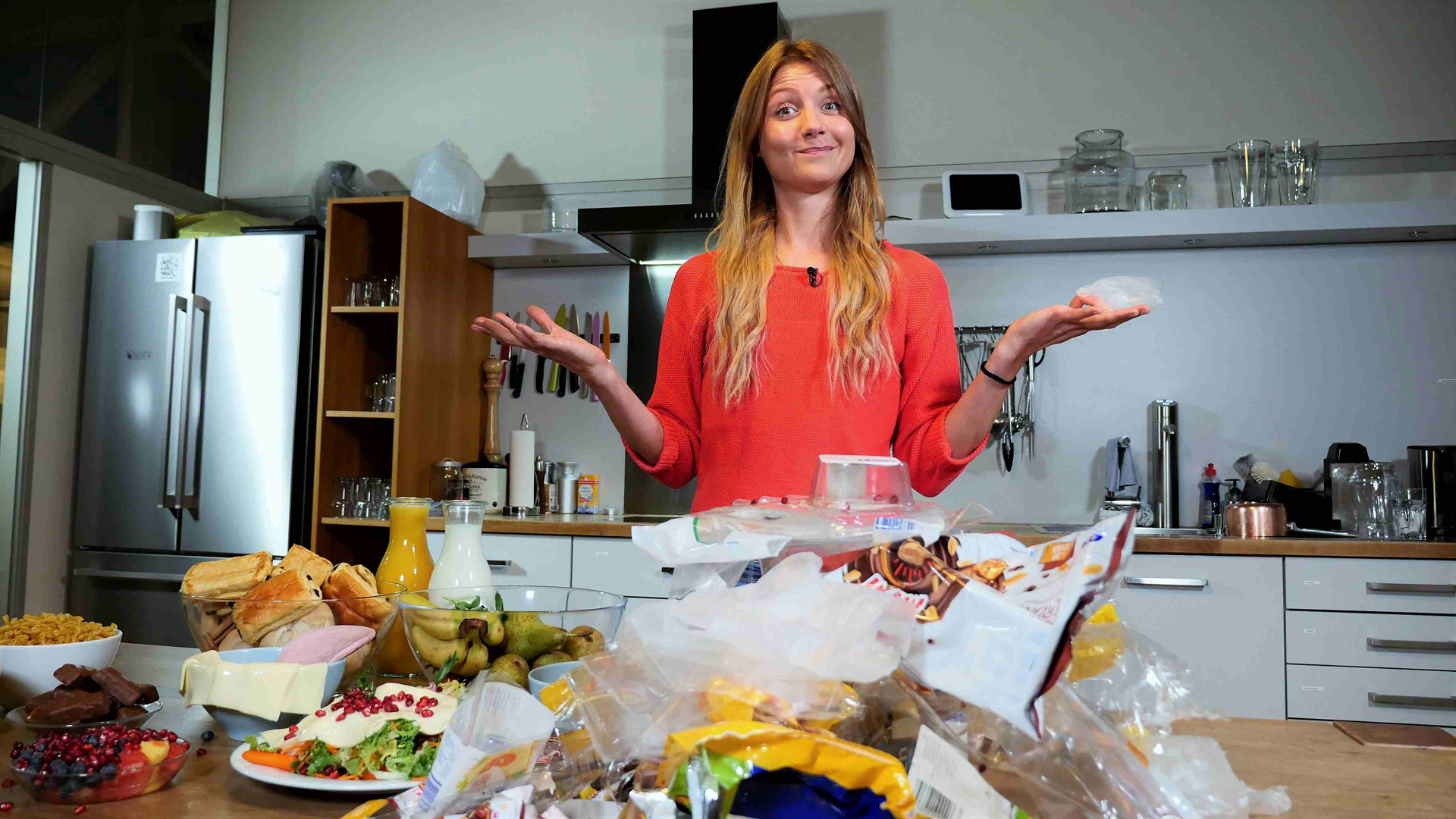 Jana steht hinter einem Küchentisch voller Lebensmittel und Plastikverpackungen.