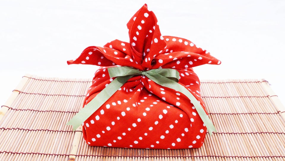 Geschenk ist mit rotem Stoff mit weißen Punkten eingepackt.