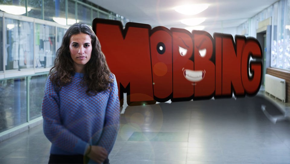 Reporterin Mona steht vor dem grafischen Schriftzug „Mobbing“, der ein bedrohliches Gesicht hat.
