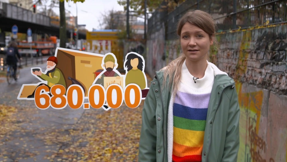 Reporterin Jana steht in einer Straße in Berlin. Neben ihr wird eine Grafik eingeblendet, die Obdachlose und die Zahl 680.000 zeigt.