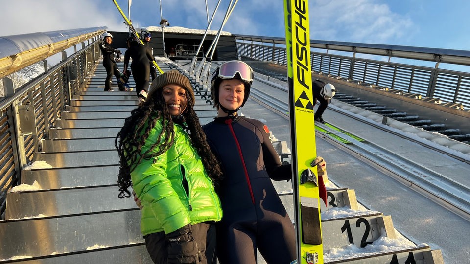 Reporterin Luam steht mit Skispringerin Nadine Färber auf einer Skisprungschanze in Oberstdorf.