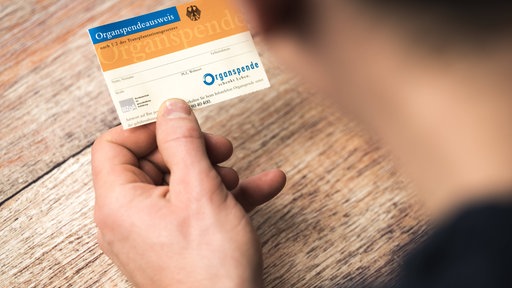 Hand hält Organspendeausweis.